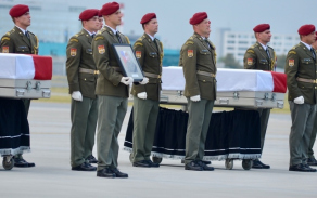 Rakev s ostatky vojáků na katafalku na letištní ploše 